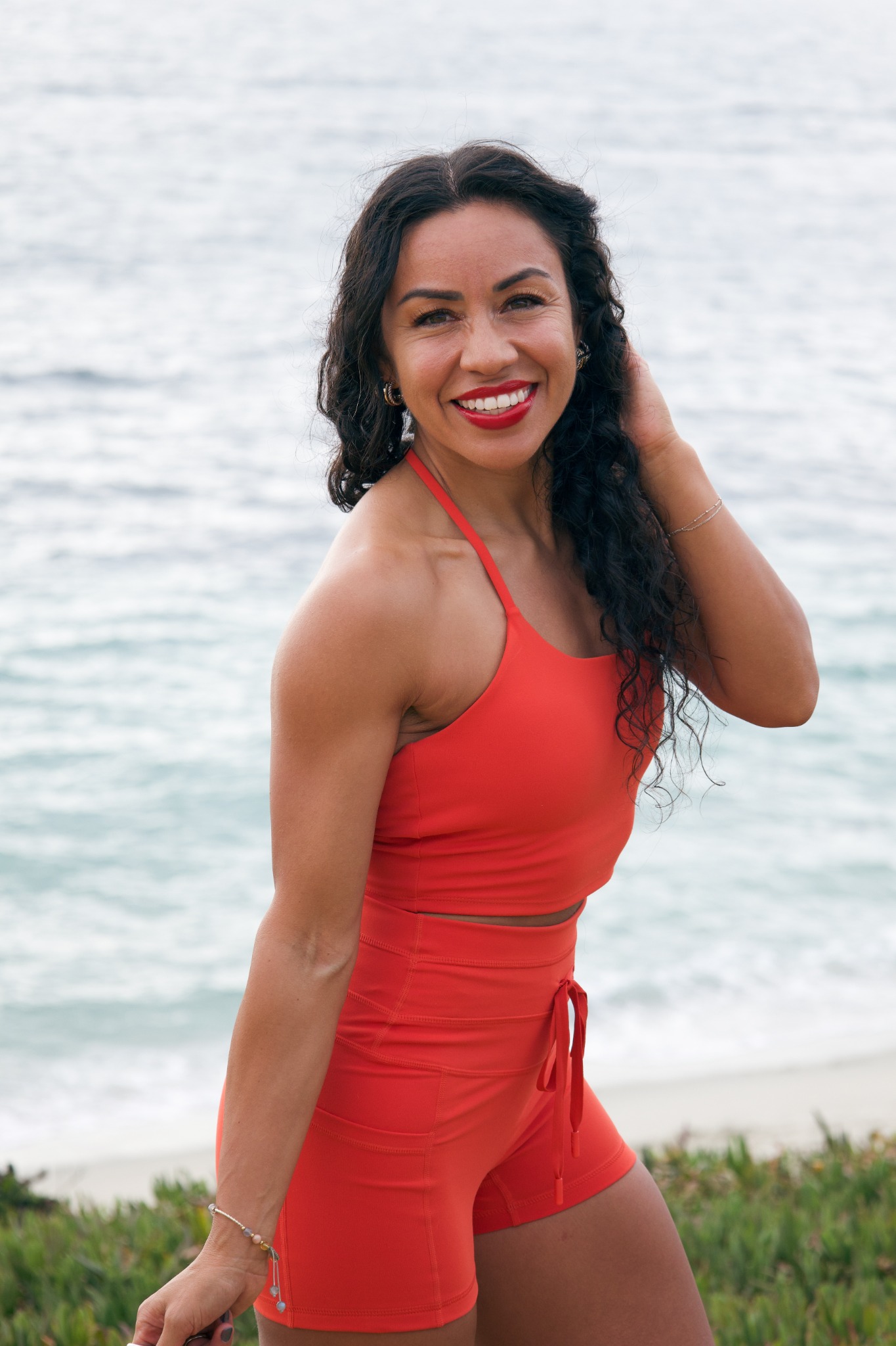 Marissa smiling outdoors in orange activewear