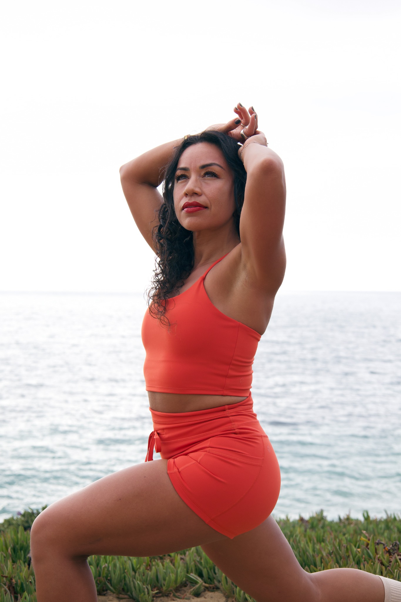 Marissa in an athletic yoga pose by the ocean